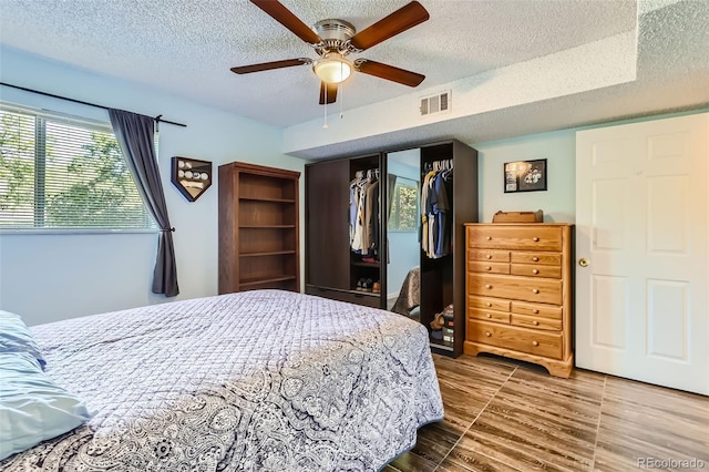 bedroom with a ceiling fan, a closet, visible vents, and a textured ceiling