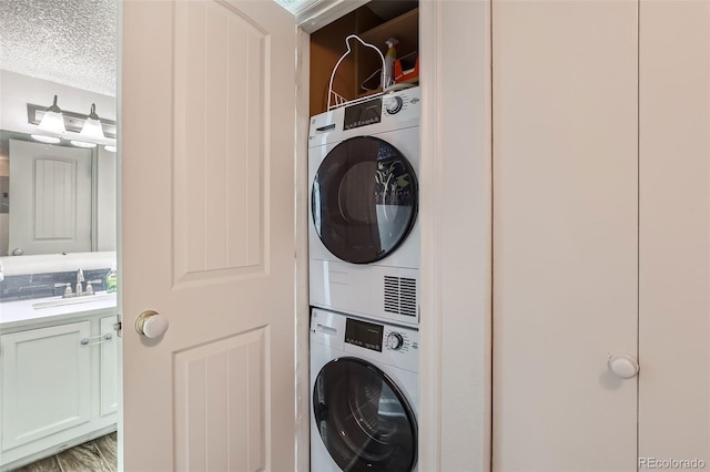 laundry room with stacked washer and dryer, a textured ceiling, laundry area, and a sink