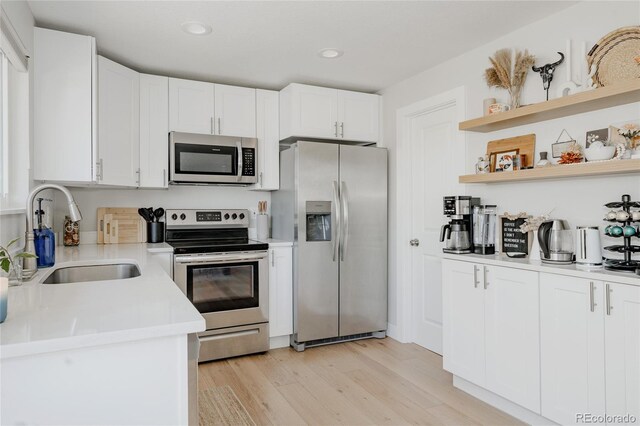 8559 W 75th Pl, Arvada, CO 80005 - kitchen with appliances with stainless steel finishes, a sink, light wood finished floors, open shelves, and light countertops
