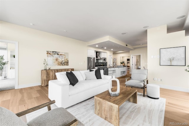 living area featuring recessed lighting, baseboards, and light wood-style floors