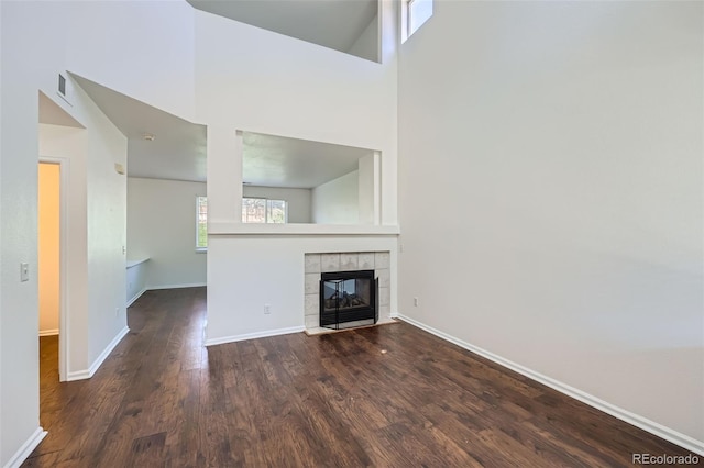 unfurnished living room featuring dark hardwood / wood-style flooring and a tile fireplace