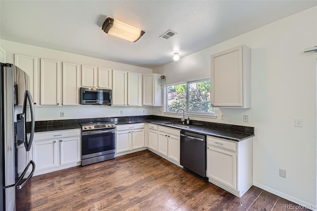 kitchen featuring appliances with stainless steel finishes, white cabinetry, sink, and dark hardwood / wood-style floors