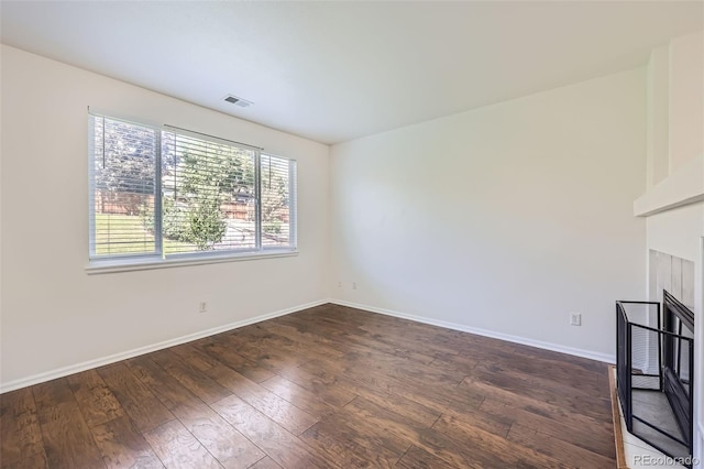 unfurnished living room with dark wood-type flooring and a tiled fireplace