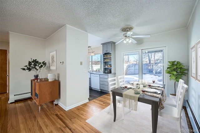 dining space featuring hardwood / wood-style floors, a baseboard radiator, sink, ornamental molding, and ceiling fan