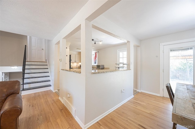 kitchen featuring light stone counters, a textured ceiling, light hardwood / wood-style floors, and a healthy amount of sunlight