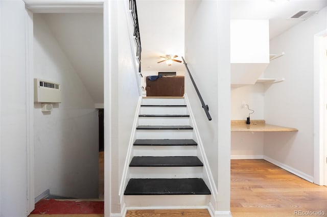 stairs featuring wood-type flooring and ceiling fan