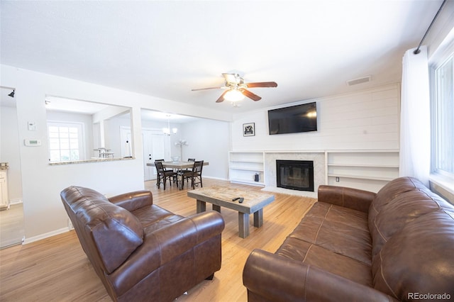 living room featuring light wood-type flooring and ceiling fan with notable chandelier