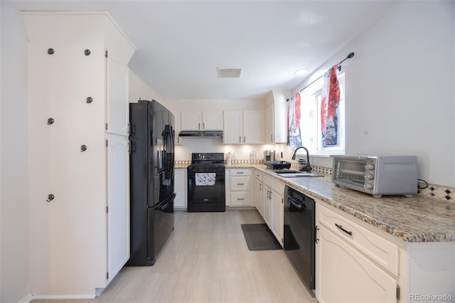 kitchen with light stone counters, sink, white cabinetry, and black appliances