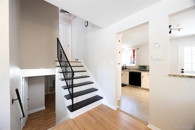 staircase featuring wood-type flooring and sink