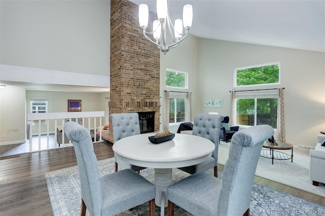 10966 W Half Moon Pass, Littleton, CO 80127 - dining space featuring high vaulted ceiling, wood finished floors, a chandelier, a fireplace, and baseboards