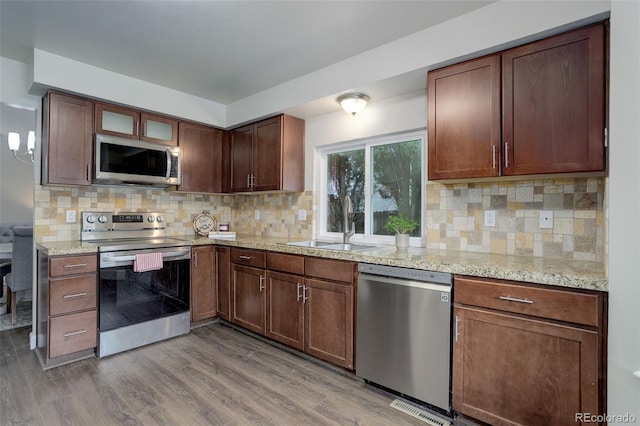 10966 W Half Moon Pass, Littleton, CO 80127 - kitchen featuring stainless steel appliances, wood finished floors, a sink, tasteful backsplash, and light stone countertops