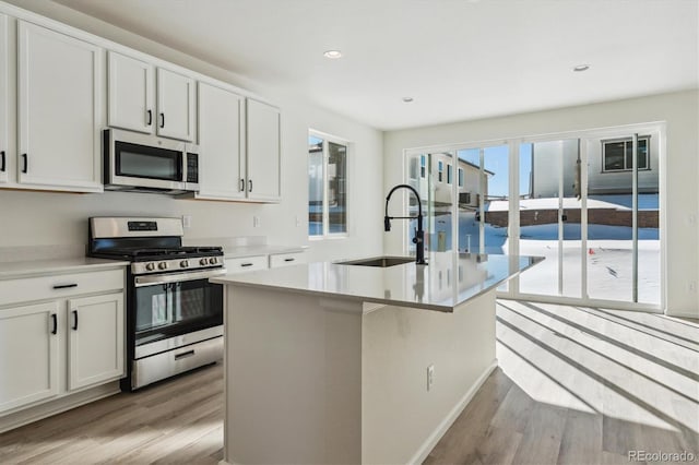 kitchen with a center island with sink, white cabinetry, sink, and appliances with stainless steel finishes