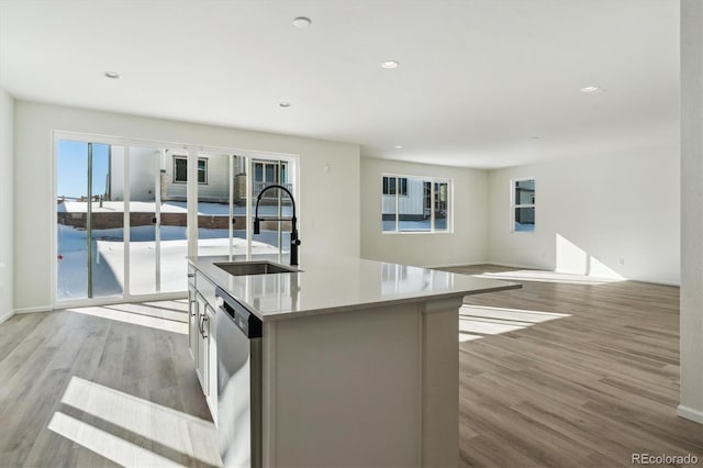 kitchen featuring a wealth of natural light, stainless steel dishwasher, a kitchen island with sink, and sink