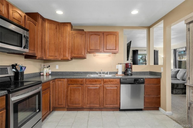 kitchen with appliances with stainless steel finishes, sink, and light carpet