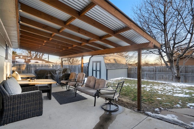 snow covered patio with a grill, an outdoor hangout area, and a storage unit