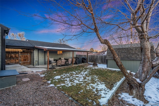 yard covered in snow with a storage unit and a patio area