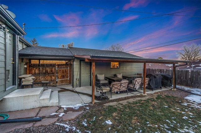 back house at dusk featuring a patio