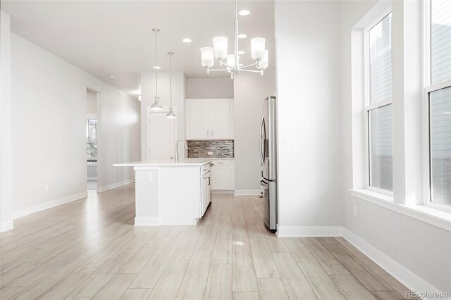 20968 E 60th Pl, Aurora, CO 80019 - kitchen featuring freestanding refrigerator, tasteful backsplash, white cabinetry, light countertops, and light wood-style flooring