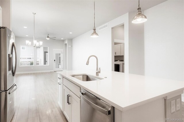 20968 E 60th Pl, Aurora, CO 80019 - kitchen with stainless steel appliances, an island with sink, open floor plan, washing machine and clothes dryer, and recessed lighting