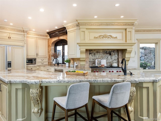 1189 Rembrandt Rd, Boulder, CO 80302 - kitchen featuring cream cabinetry, appliances with stainless steel finishes, a kitchen island with sink, light stone countertops, and plenty of natural light