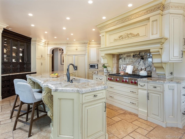 1189 Rembrandt Rd, Boulder, CO 80302 - kitchen featuring cream cabinets, stainless steel appliances, arched walkways, recessed lighting, and an island with sink