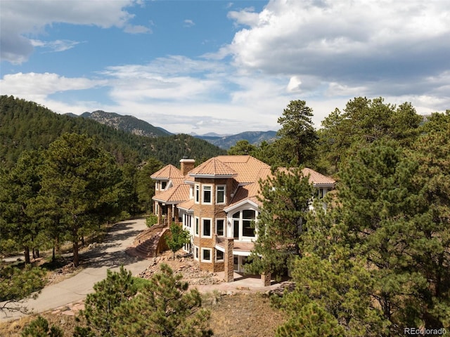 1189 Rembrandt Rd, Boulder, CO 80302 - view of front facade featuring a mountain view, a wooded view, a tiled roof, and a chimney