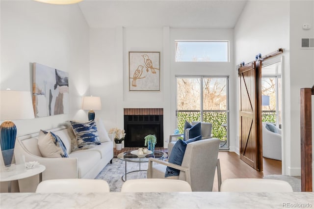 living area with a brick fireplace, visible vents, and wood finished floors