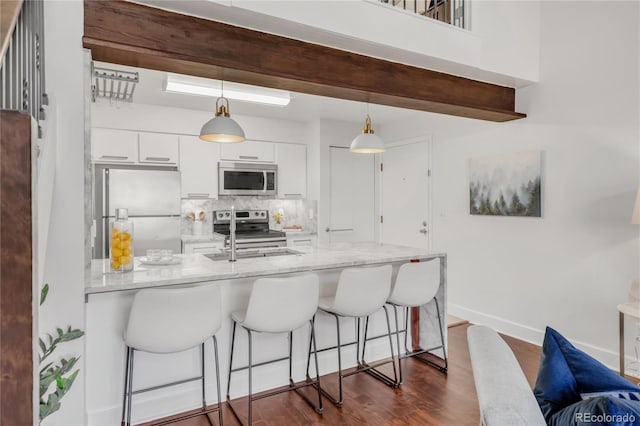 kitchen with stainless steel appliances, a breakfast bar, backsplash, and white cabinetry