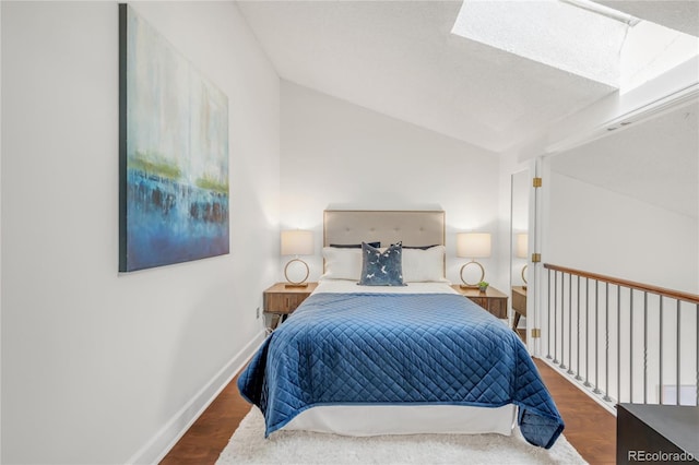 bedroom with lofted ceiling with skylight, baseboards, and wood finished floors