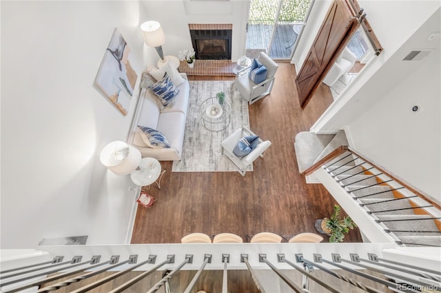 interior space with a brick fireplace, stairway, visible vents, and wood finished floors