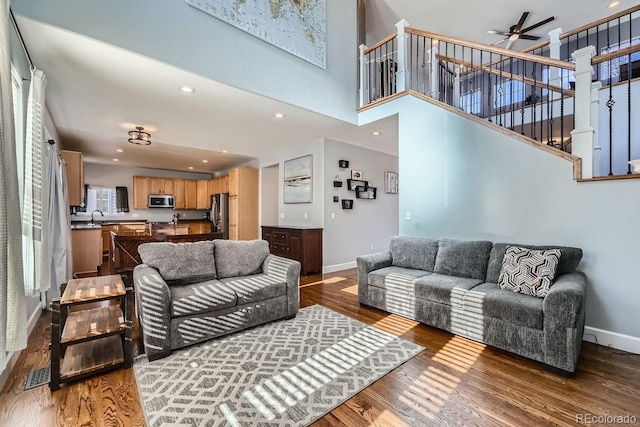 living room featuring hardwood / wood-style flooring, ceiling fan, sink, and a high ceiling