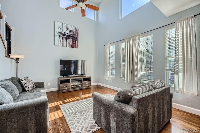 living room with ceiling fan, plenty of natural light, hardwood / wood-style floors, and a high ceiling