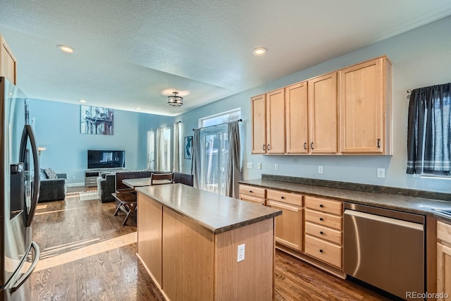 kitchen with light brown cabinets, wood-type flooring, stainless steel appliances, and a kitchen island