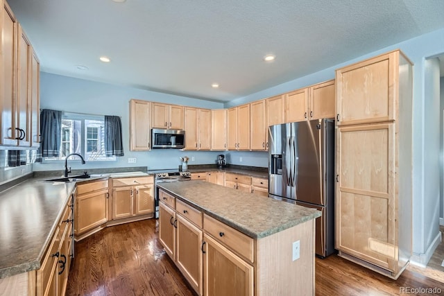 kitchen with stainless steel appliances, light brown cabinetry, sink, and a kitchen island