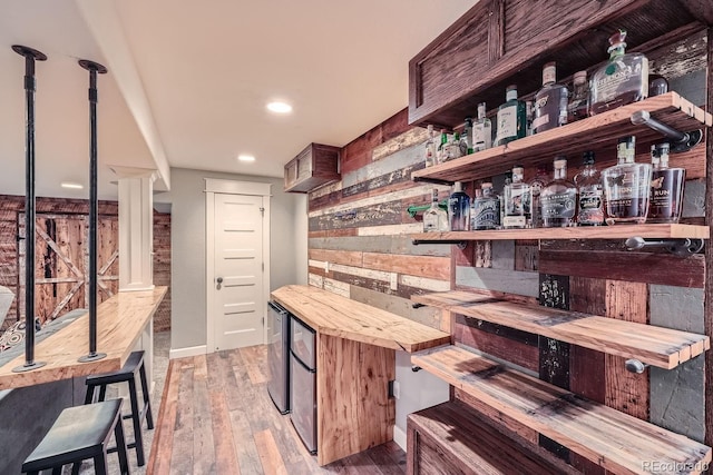 bar featuring light hardwood / wood-style flooring and wooden counters