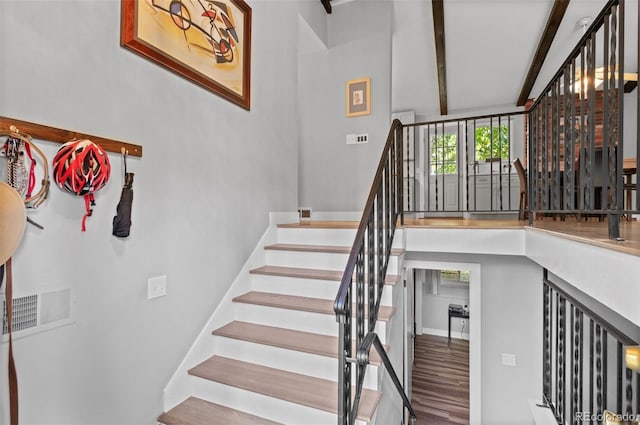 staircase featuring hardwood / wood-style flooring and beamed ceiling