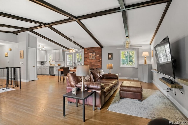 living room with a wealth of natural light, lofted ceiling with beams, and light hardwood / wood-style flooring