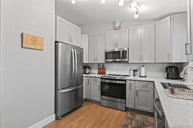 kitchen featuring lofted ceiling, light hardwood / wood-style flooring, sink, appliances with stainless steel finishes, and tasteful backsplash