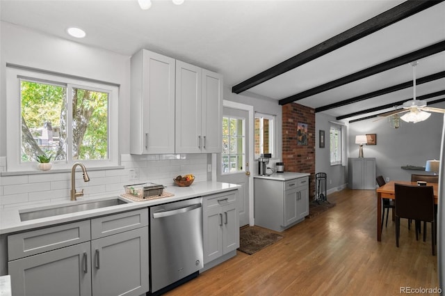 kitchen with stainless steel dishwasher, sink, beam ceiling, and plenty of natural light