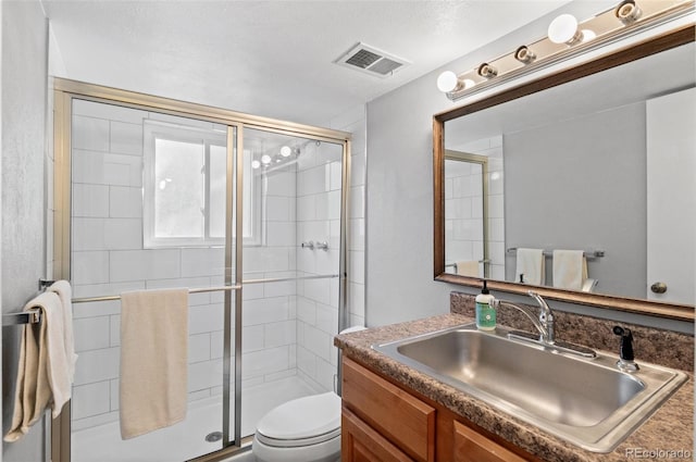 bathroom featuring a shower with door, toilet, a textured ceiling, and vanity