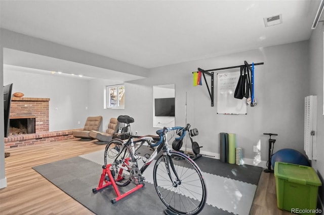 workout room featuring a brick fireplace and hardwood / wood-style floors