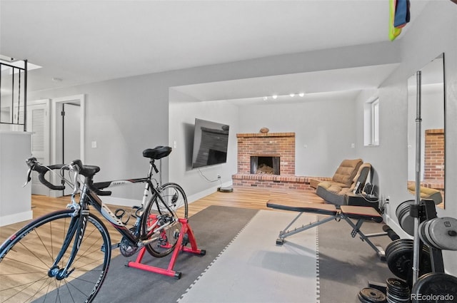 workout area with hardwood / wood-style flooring and a brick fireplace