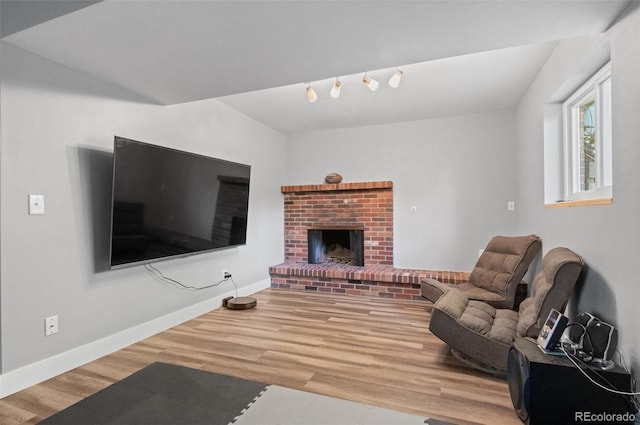 living room with a brick fireplace and hardwood / wood-style floors