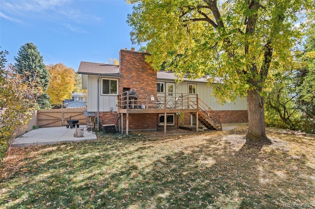 rear view of house featuring a wooden deck, a yard, and a patio