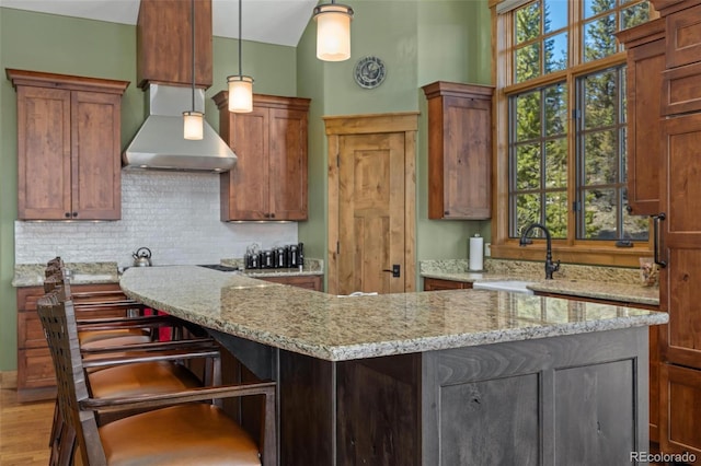 kitchen with a kitchen breakfast bar, light hardwood / wood-style floors, light stone counters, and sink