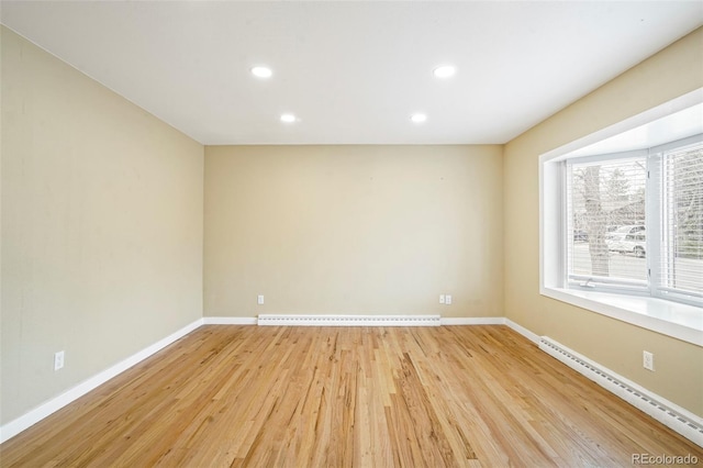 unfurnished room with baseboard heating and light hardwood / wood-style floors