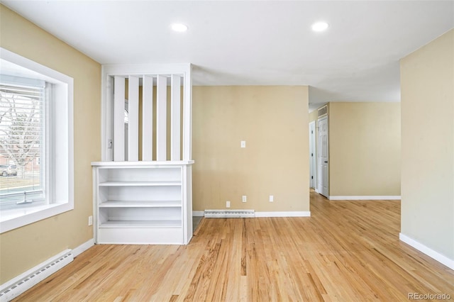 spare room with a healthy amount of sunlight, light hardwood / wood-style floors, and a baseboard radiator