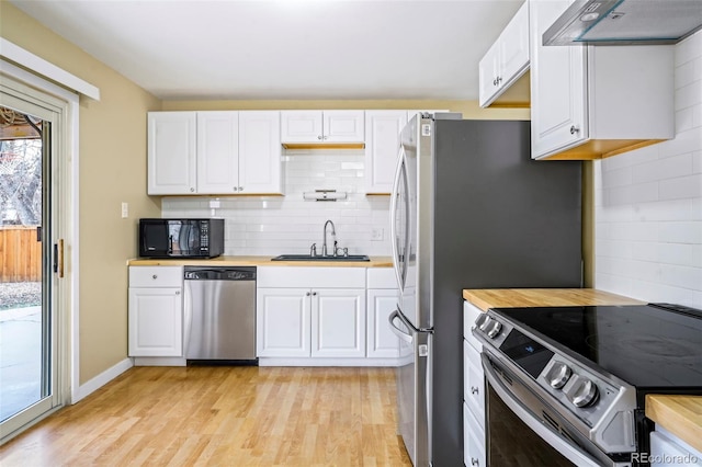 kitchen with white cabinetry, sink, stainless steel appliances, tasteful backsplash, and range hood