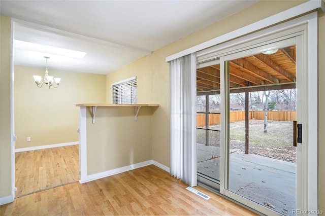 doorway featuring light hardwood / wood-style flooring, a wealth of natural light, and a notable chandelier