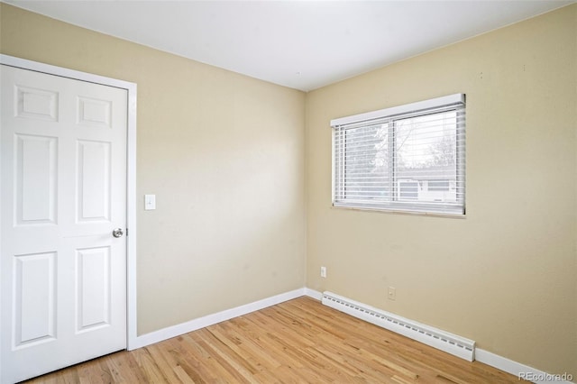 spare room with wood-type flooring and a baseboard heating unit